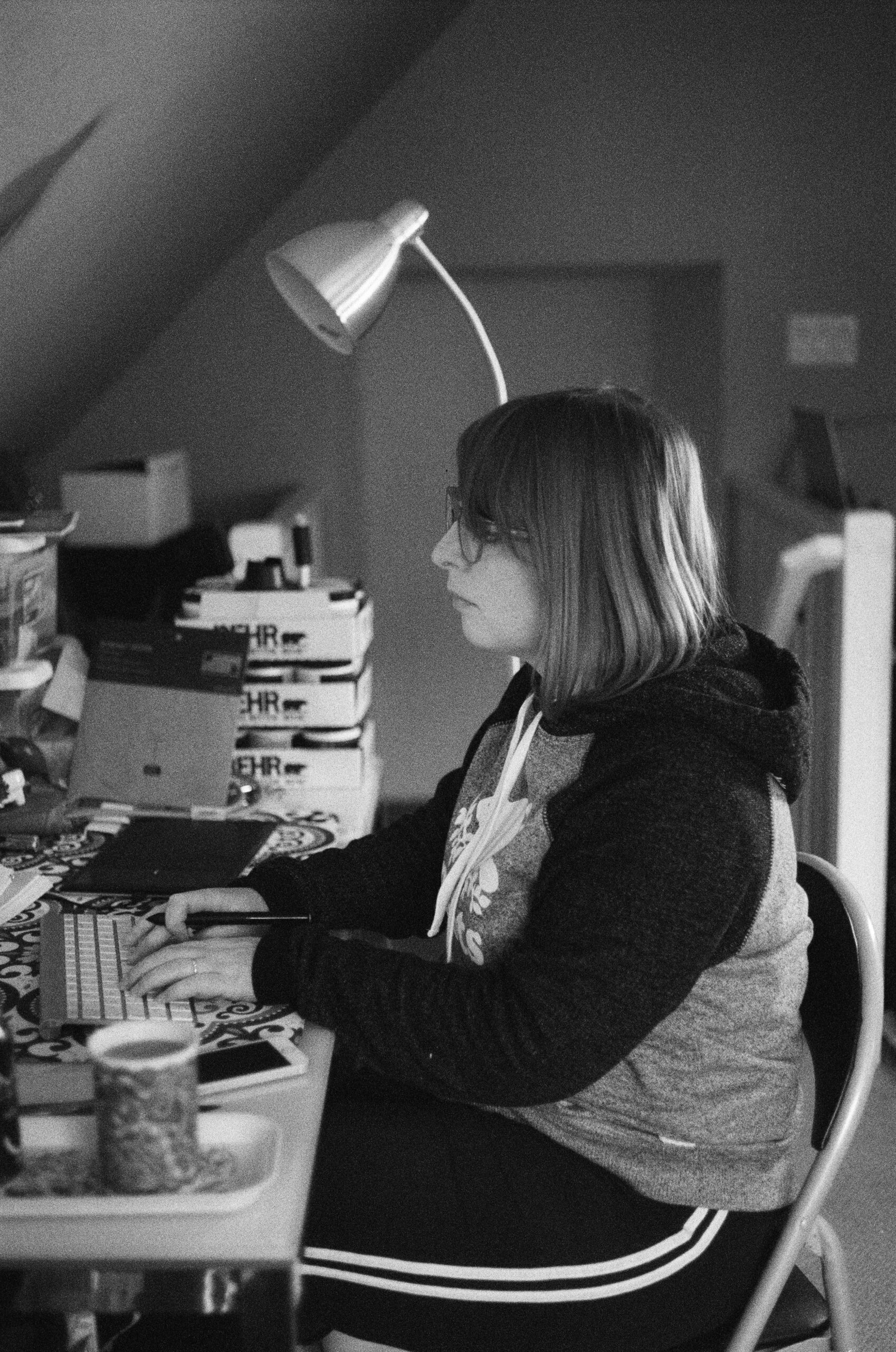 A woman with shoulder length hair sits typing at a desk